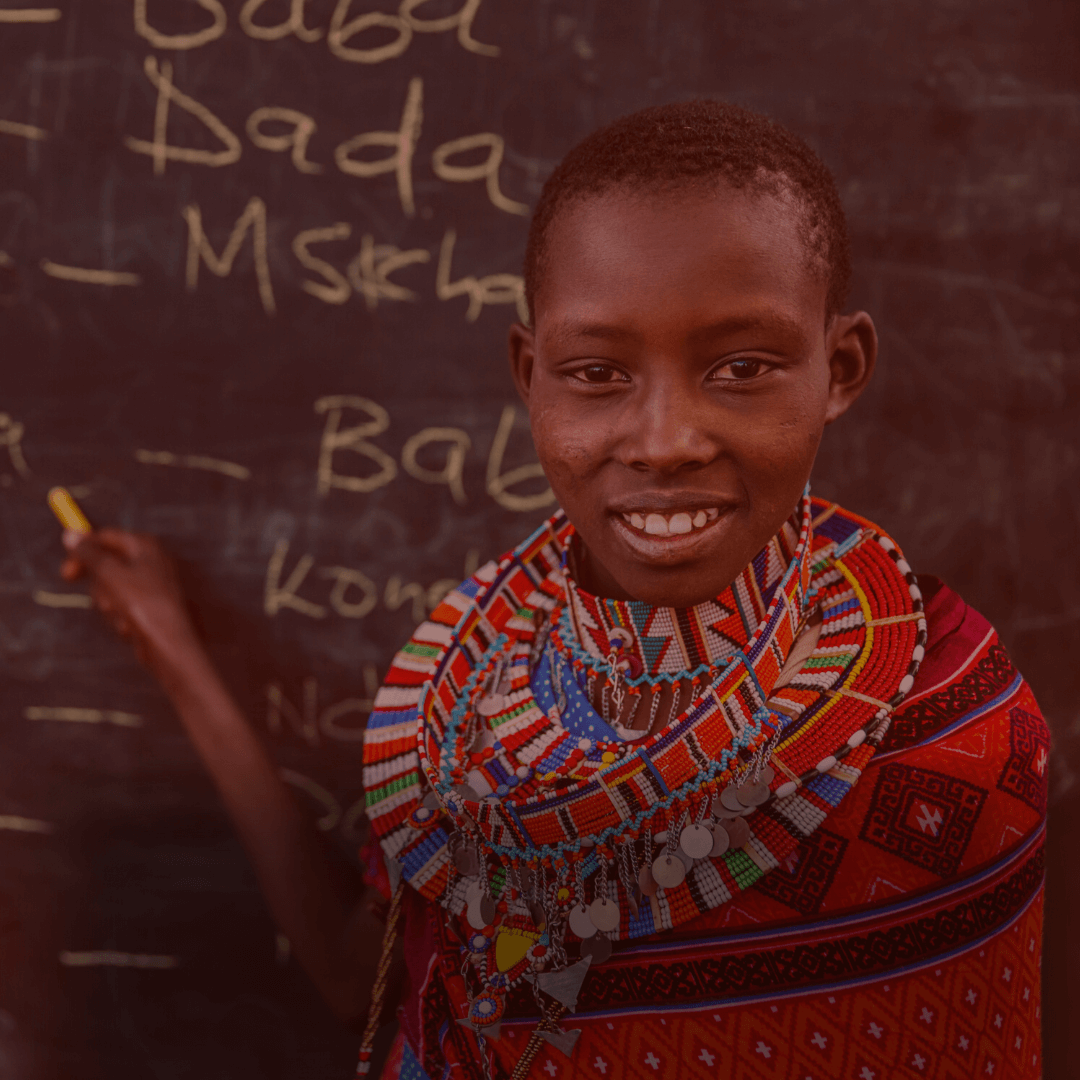 Maasai girl is standing in front of writing board.